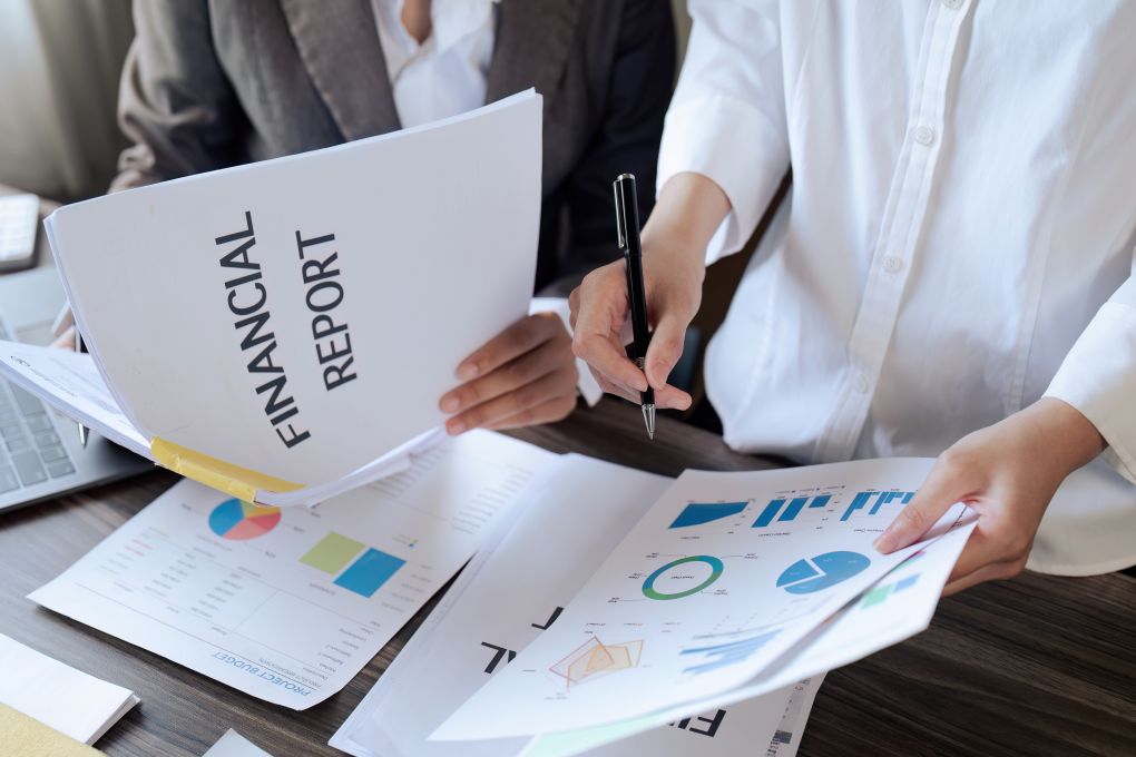 two professionals reviewing a financial report with charts and graphs, representing charity financial reporting, donor reporting, and funding report requirements for UK charities